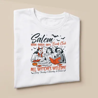 Vintage illustration of witches reading books with Halloween theme — printed on a unisex t-shirt (angled view)