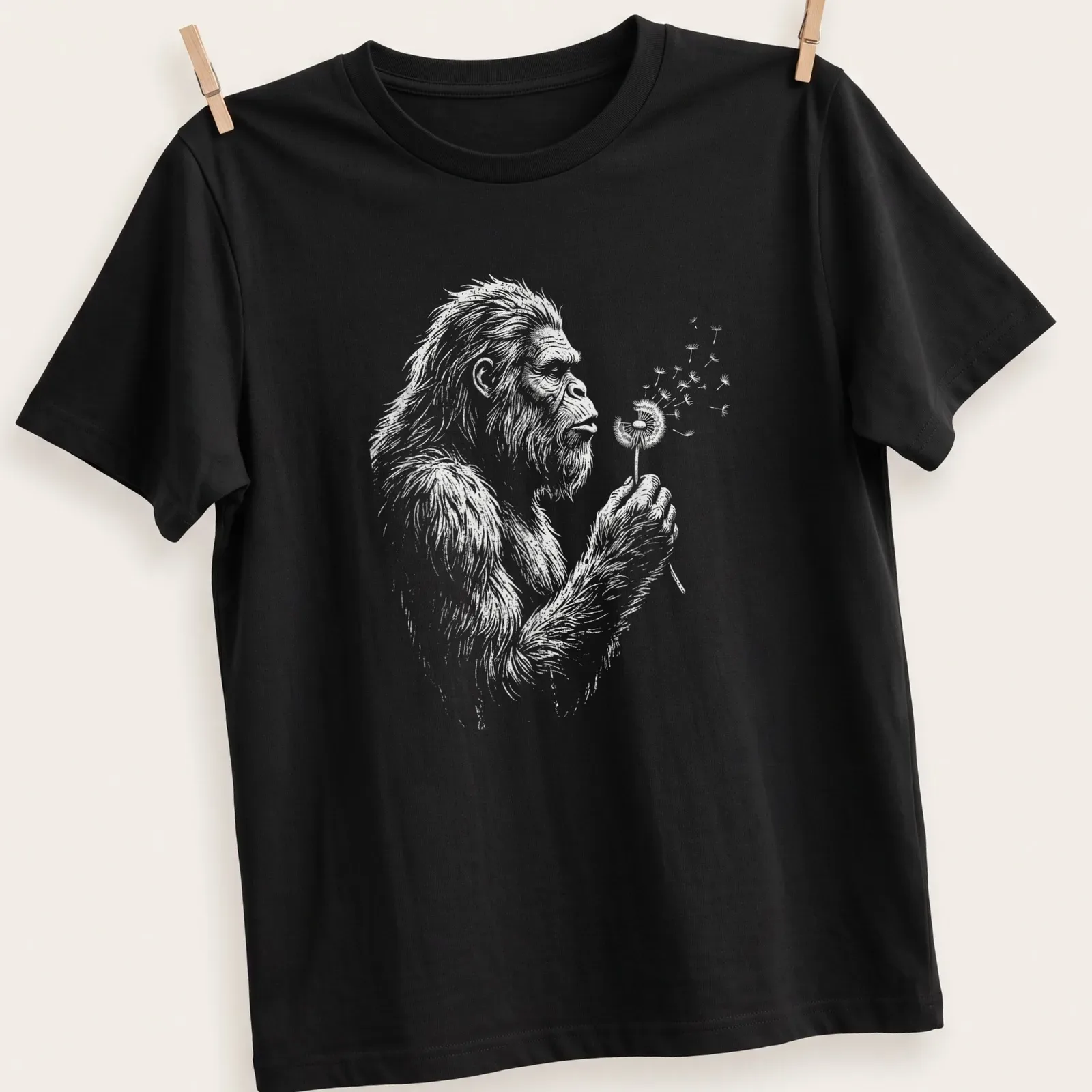 Vintage Bigfoot T-shirt with whimsical illustration of Sasquatch blowing dandelion seeds — printed on a unisex t-shirt