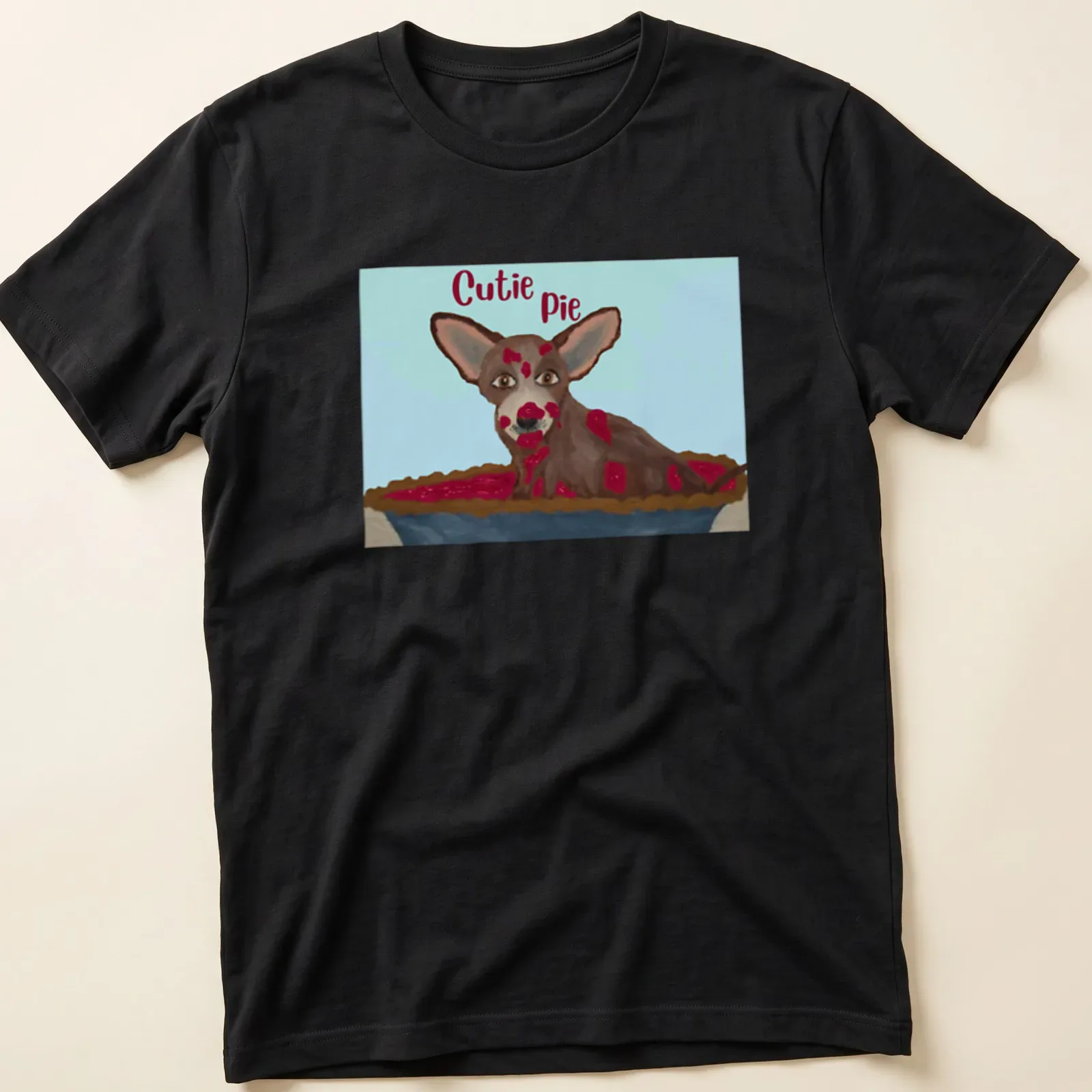 Whimsical illustration of a Chihuahua with the text 'Cutie Pie' in brown and cream colors — printed on a unisex t-shirt