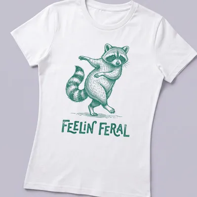 Green vintage illustration of a playful raccoon with the text 'Feelin' Feral' — printed on a women's shirt