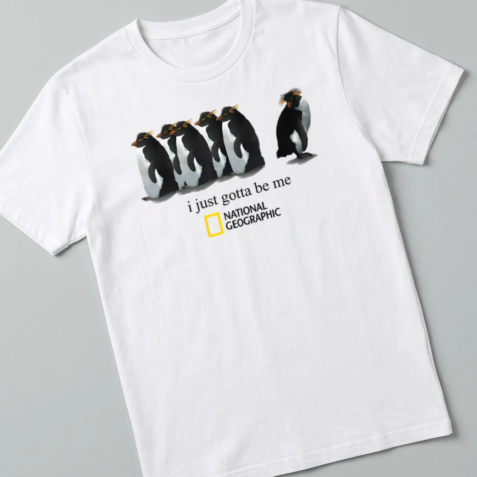 Illustrative penguin design with the text 'i just gotta be me' in black and orange. — printed on a unisex t-shirt