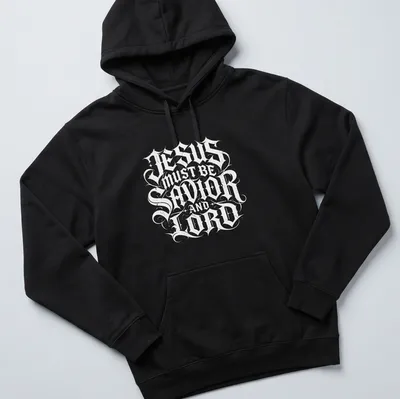 Ornate lettering of 'Jesus Must Be Savior And Lord' in black and white — printed on a unisex hoodie