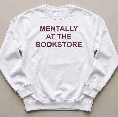 Bold typography t-shirt with the text 'Mentally At The Bookstore' in maroon and white — printed on a unisex sweatshirt