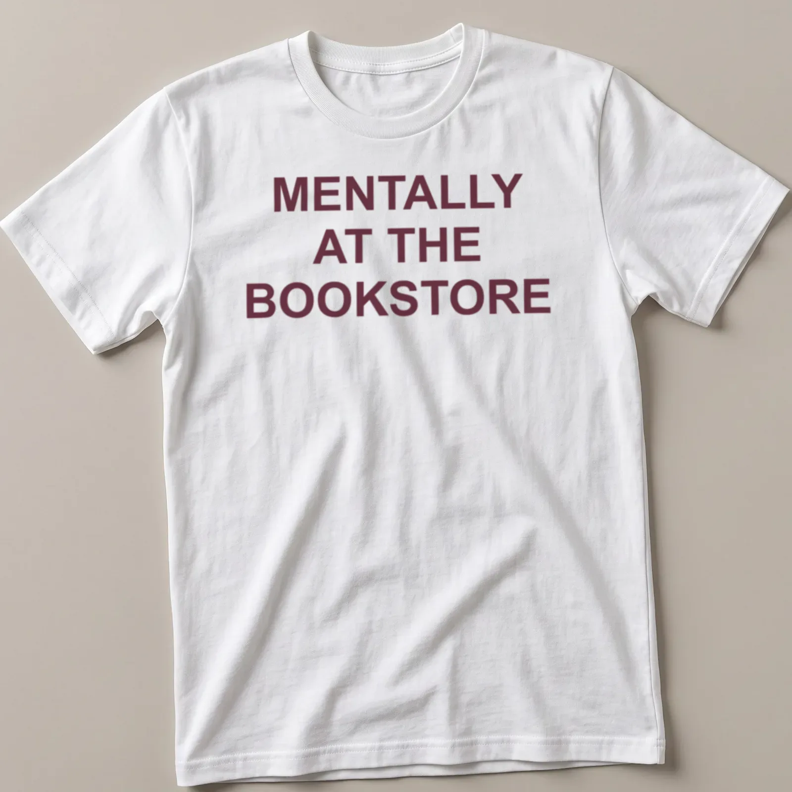 Bold typography t-shirt with the text 'Mentally At The Bookstore' in maroon and white — printed on a unisex t-shirt