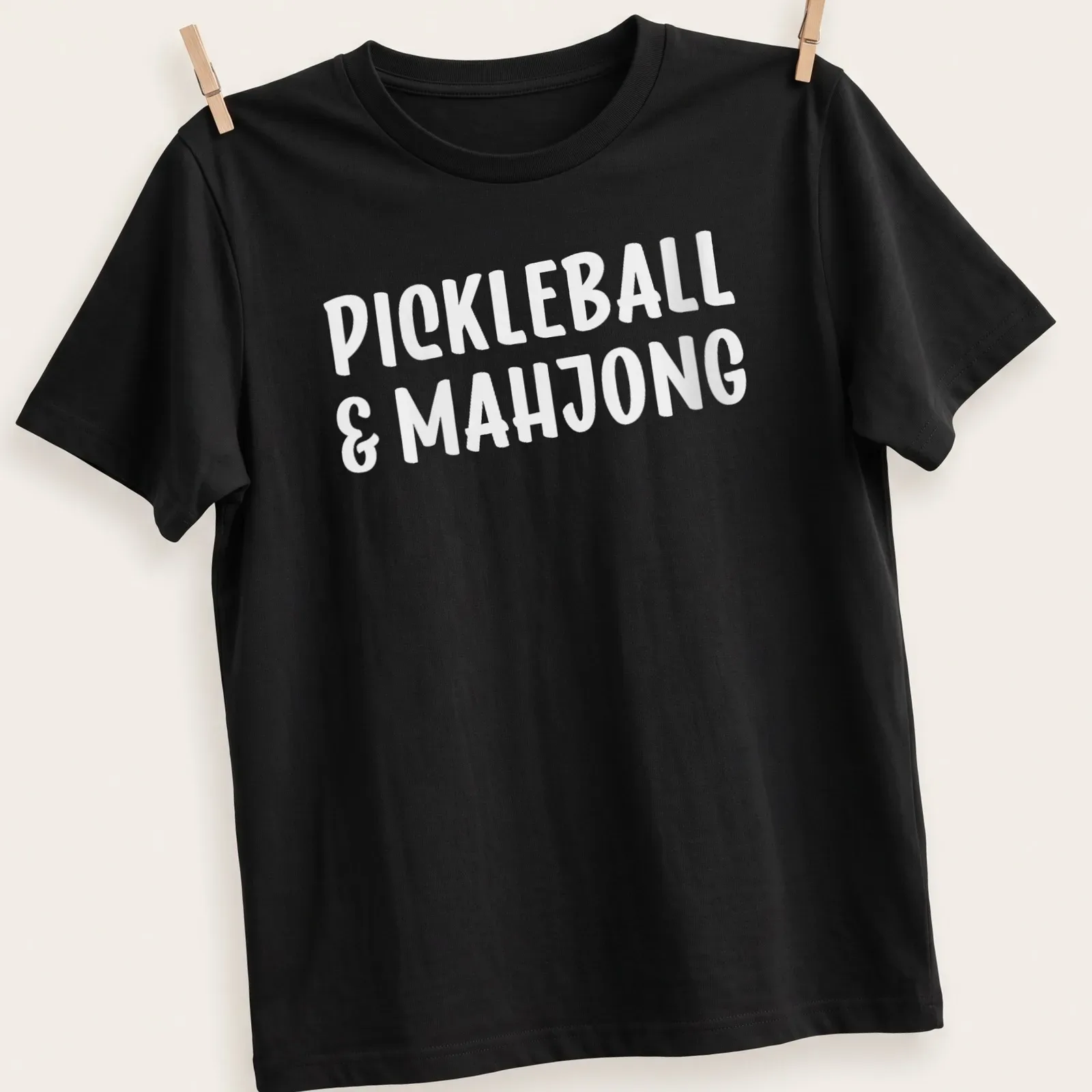 Bold typography design featuring pickleball and mahjong text in white — printed on a unisex t-shirt