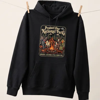 Vintage illustration of Bigfoot and Mothman around a campfire with text about protecting national parks. — printed on a unisex hoodie