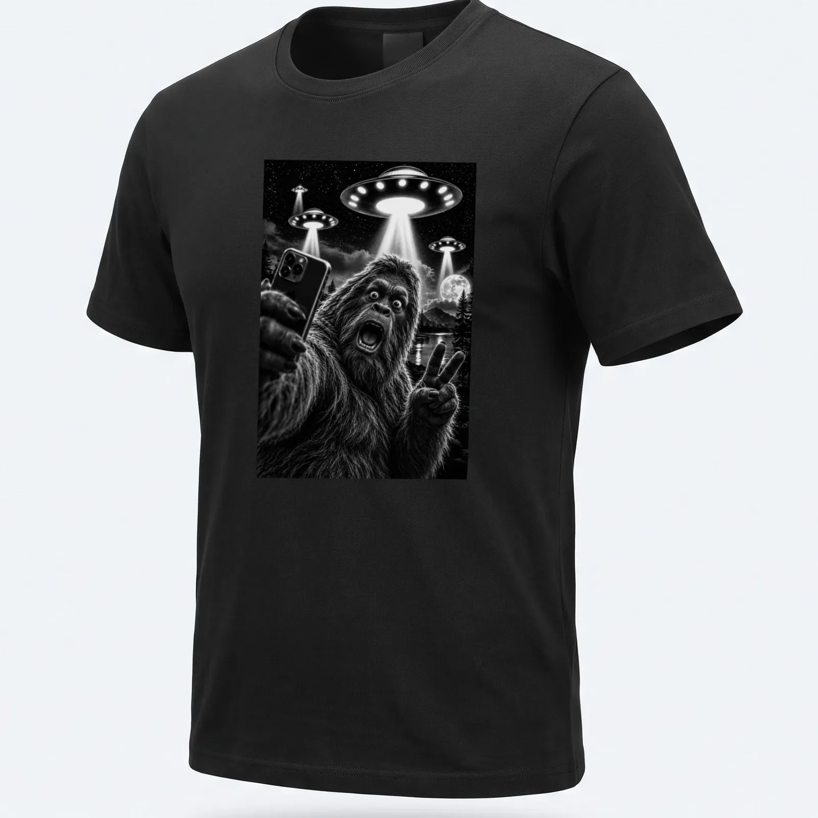 Realistic black and white print of Sasquatch taking a selfie with UFOs — printed on a unisex t-shirt