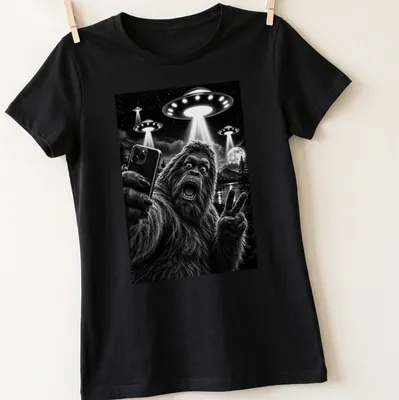 Realistic black and white print of Sasquatch taking a selfie with UFOs — printed on a women's shirt