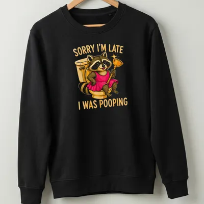 Cartoon raccoon in a dress with humorous text about being late due to pooping — printed on a unisex sweatshirt