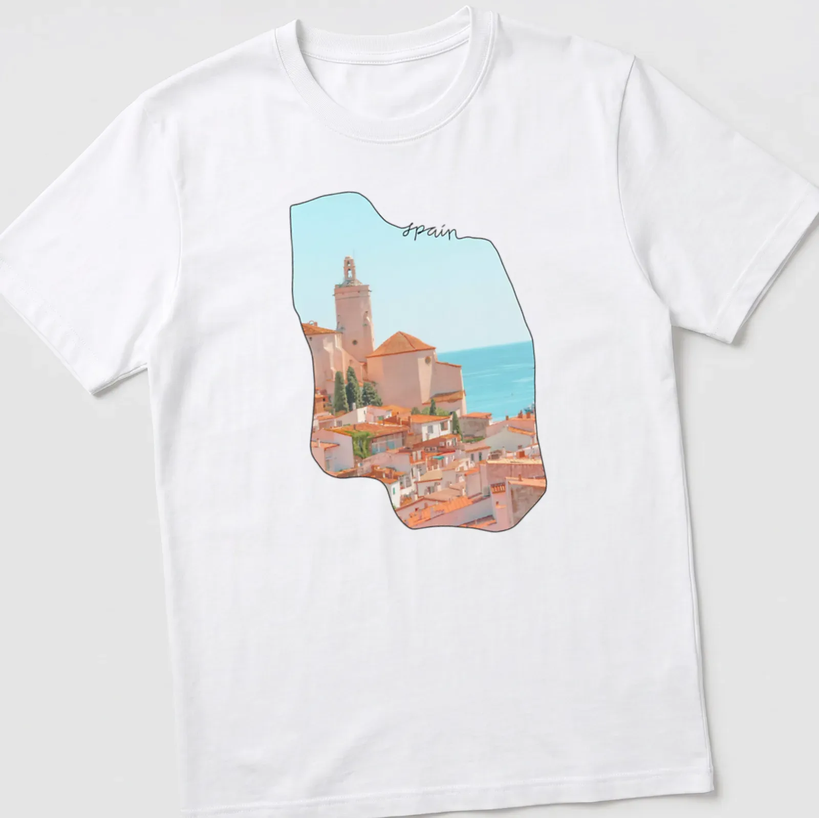 Watercolor coastal village scene with 'spain' text in soft colors — printed on a unisex t-shirt