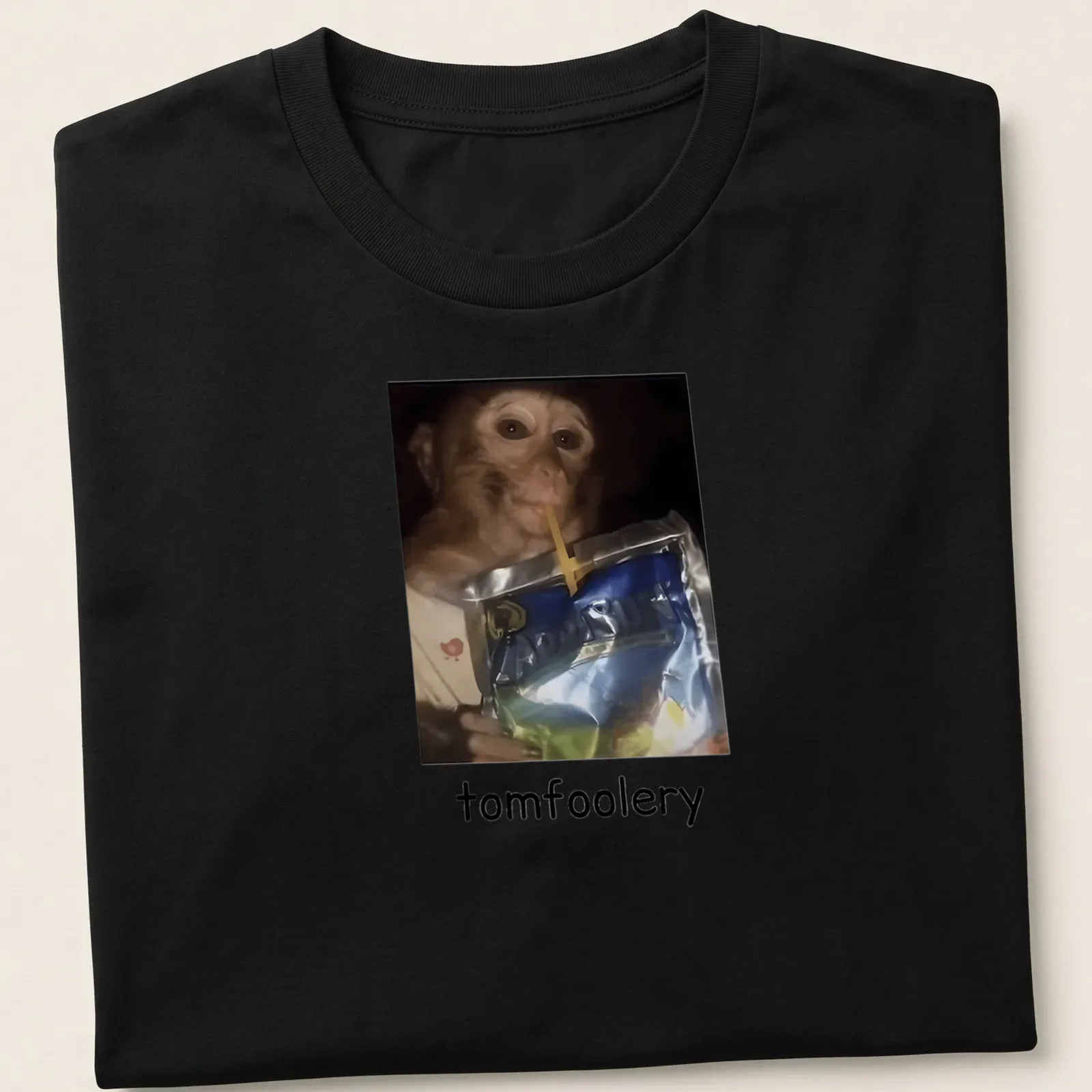 Realistic print of a monkey drinking juice from a pouch, featuring vibrant colors — printed on a unisex t-shirt