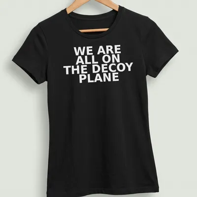 Bold typography t-shirt featuring the phrase 'WE ARE ALL ON THE DECOY PLANE' — printed on a women's shirt