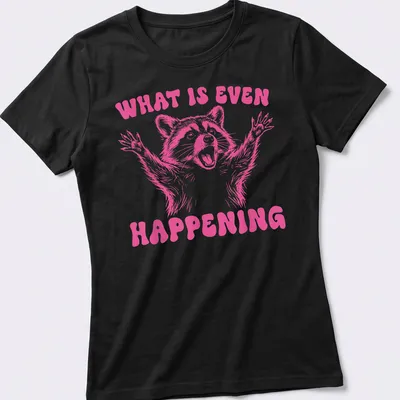 Vintage-style pink t-shirt featuring a quirky raccoon and humorous text — printed on a women's shirt